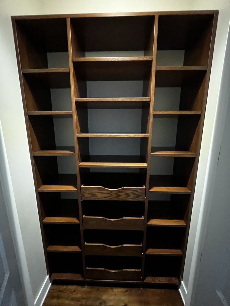Dark stained wood closet system with open shelving and center drawer stack