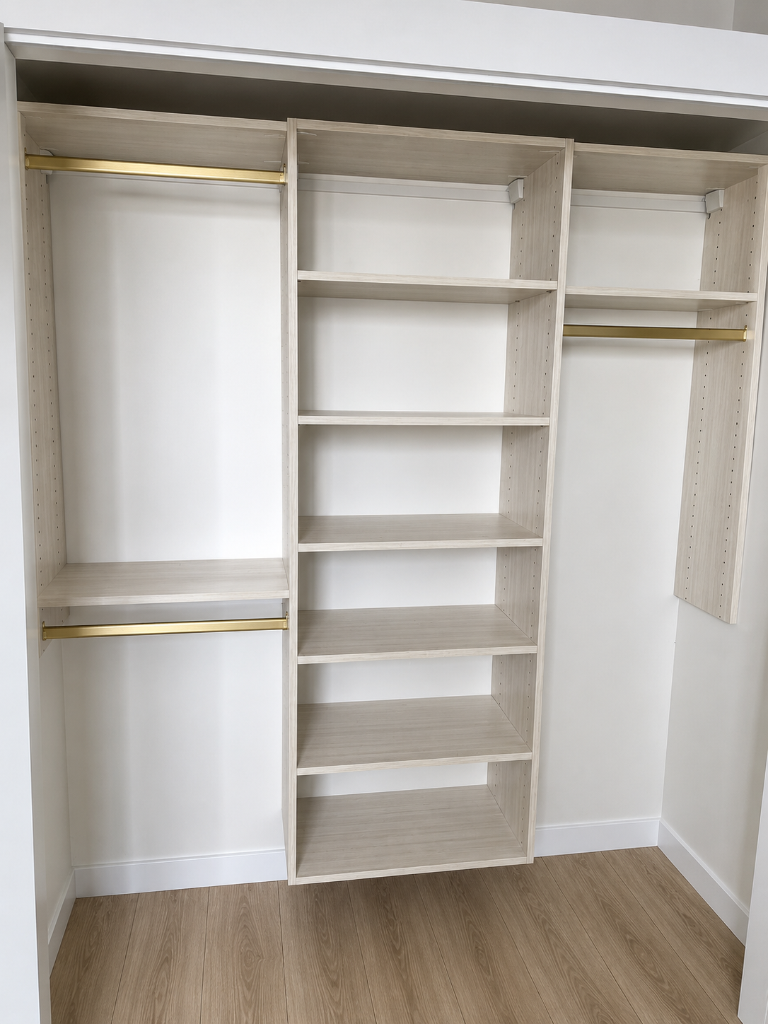 Light oak reach-in closet system with brass hanging rods and adjustable shelving