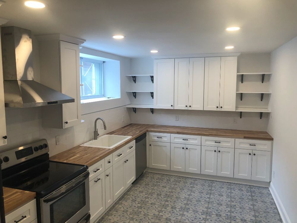 White shaker kitchen with butcher block countertops and open black-bracket shelving