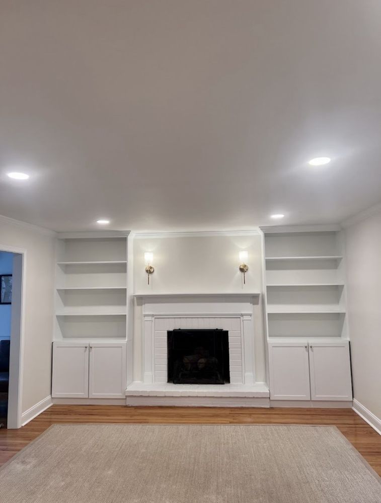 White built-in bookshelves and cabinets flanking a painted brick fireplace