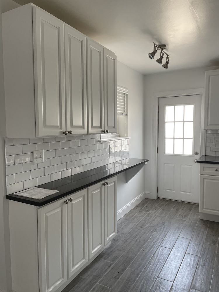 White raised-panel cabinetry with subway tile backsplash and black countertop